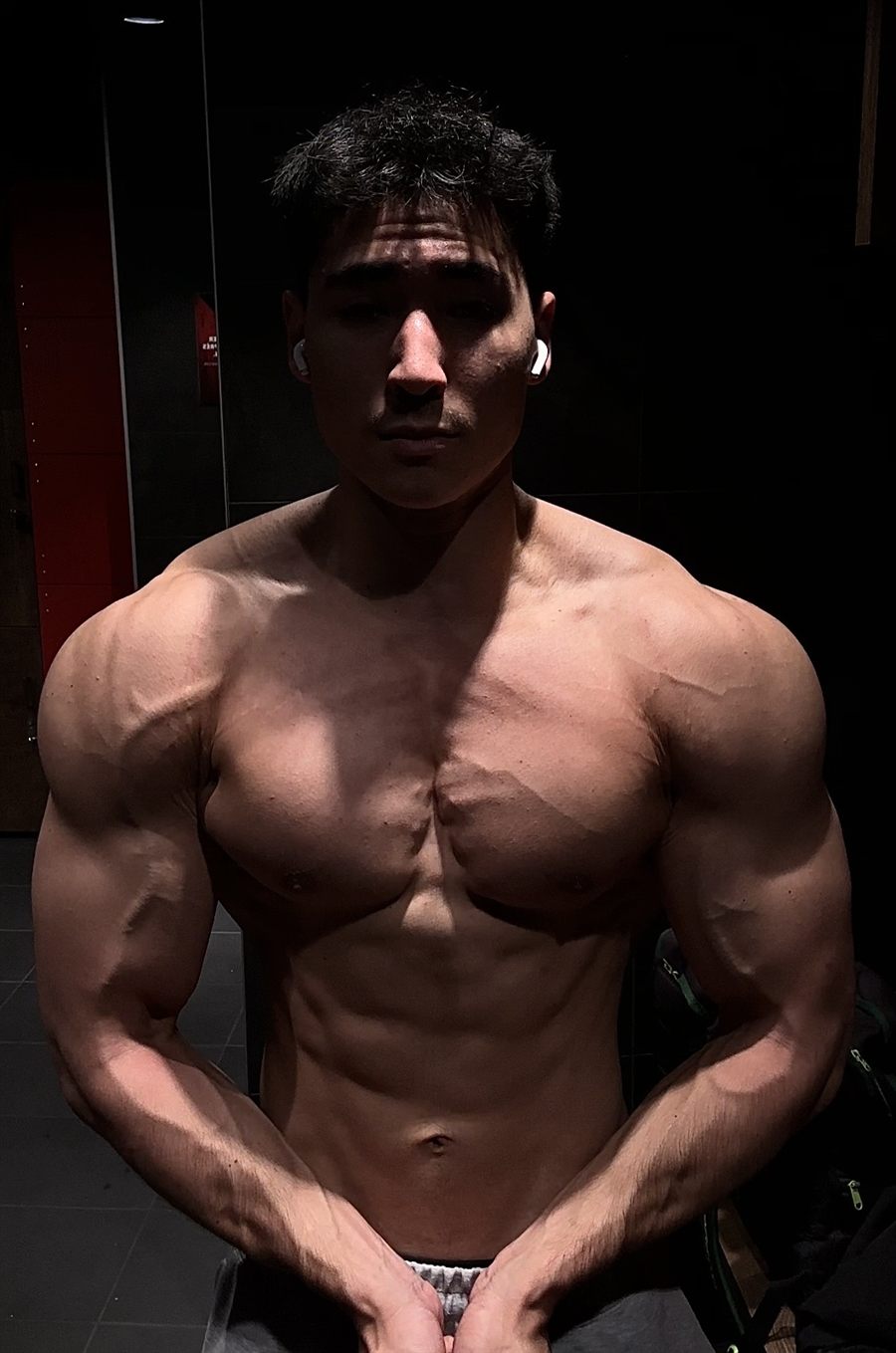 Alexandre torse nu dans un vestiaire de salle de sport, de face